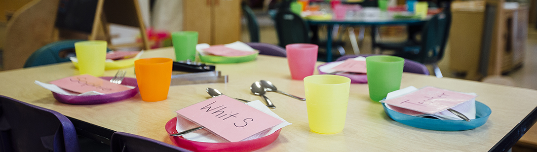 A table with children's plastic cutlery on it, as well as name tags.