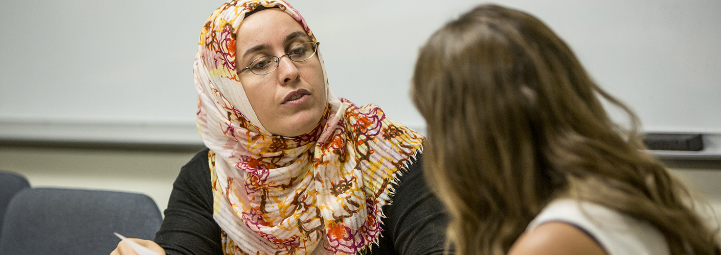 A woman in hijab and glasses consults with a student.