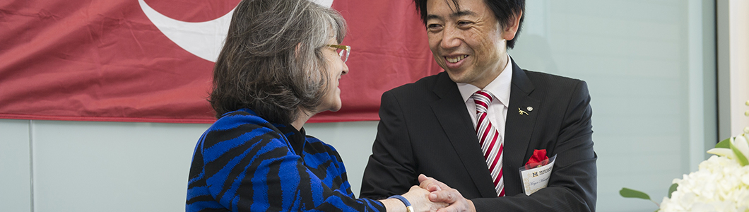 President Waded Cruzado, a middle-aged woman in a blue suit, is pictured shaking the hand of a Japanese dignitary.