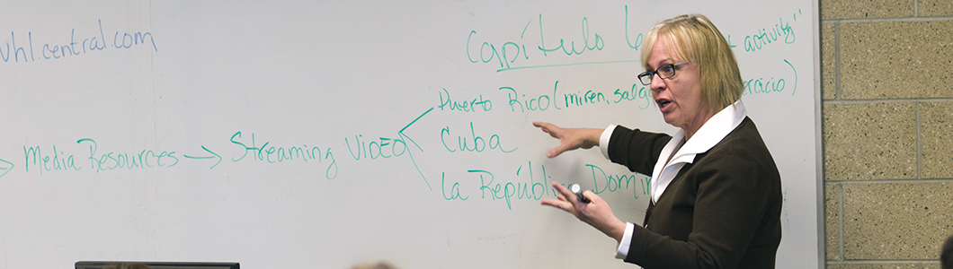 A professor gestures towards a series of Latin American countries on a whiteboard.