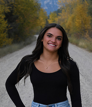 A girl with long dark hair and a black shirt standing in a road