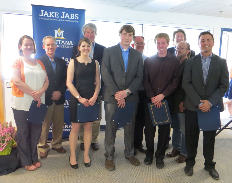 Ten faculty and students stand in front of a blue banner