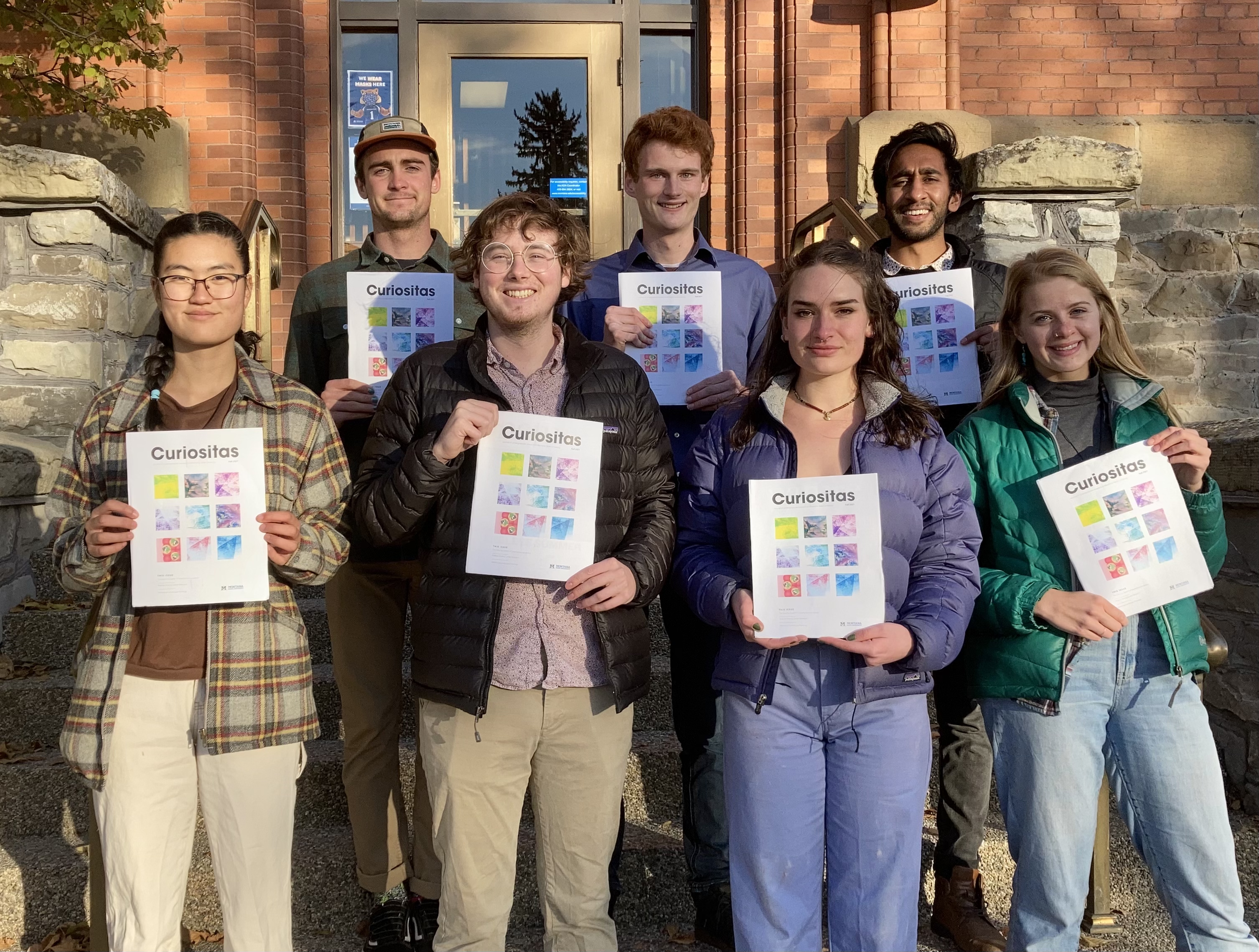 The 2021-2022 Curiositas editorial board stands outside holding the Fall 2021 edition.