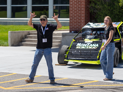 Two 4-Hers standing next to a car