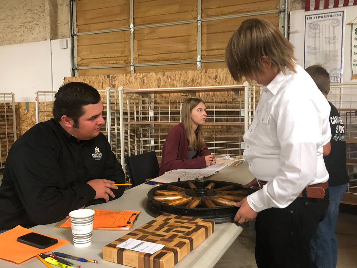 A young boy talking to an adult, showing the adult their woodworking pieces