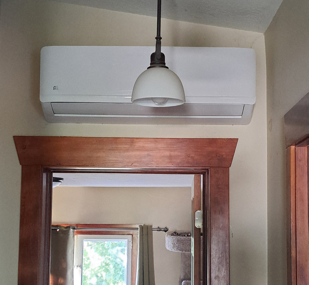 A white heater attached above an open door frame.