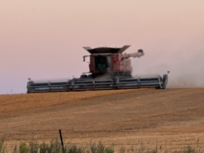 Winterizing farm equipment feature image a tractor drives across a field at dusk