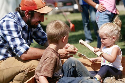 male and two children looking at bones