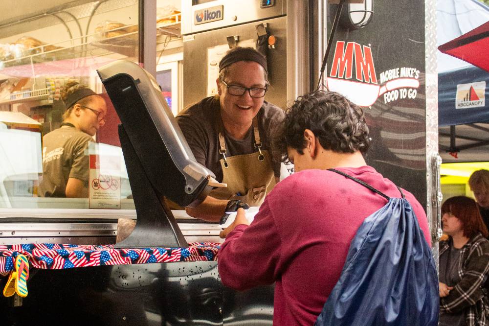 person receiving food from another person that's inside a food truck