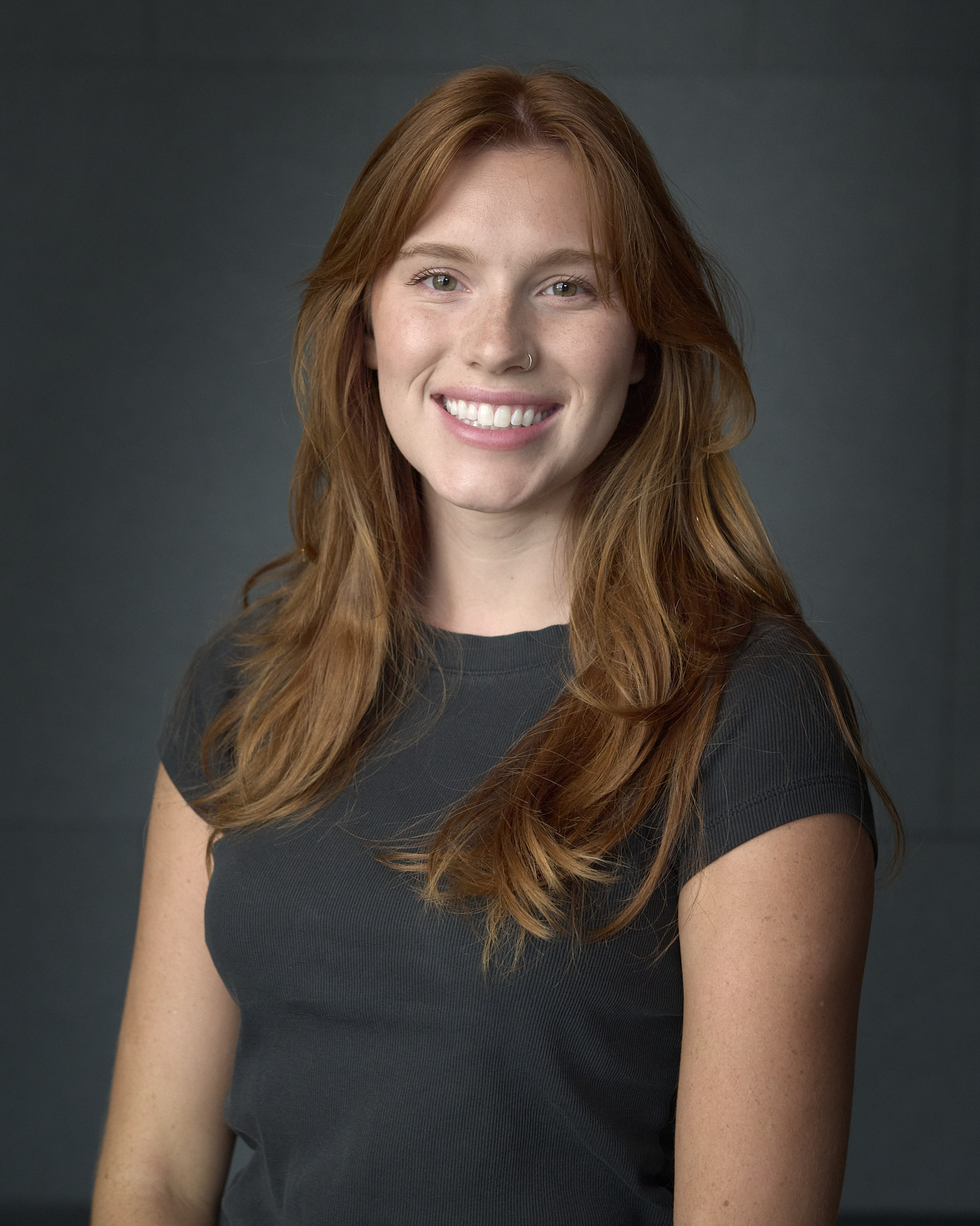 Portrait picture of a woman with long orange hair and a black shirt