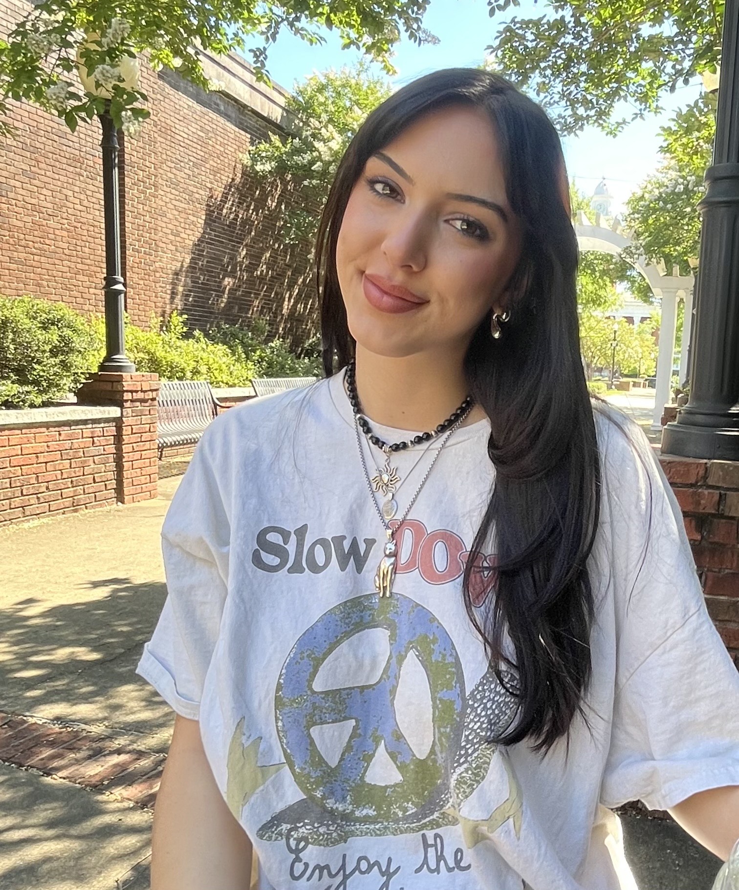 A person with short black hair wearing a white long sleeved button up shirt