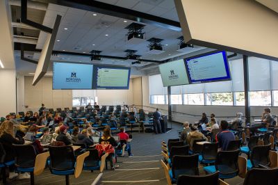 Large circular lecture hall in NAH 103 with students observing an instructor give a lecture
